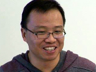 a man wearing glasses and smiling at the camera
