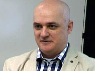 a man wearing a suit and tie smiling at the camera