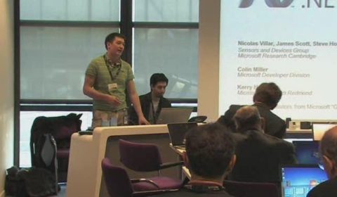 a group of people sitting at a table in front of a laptop