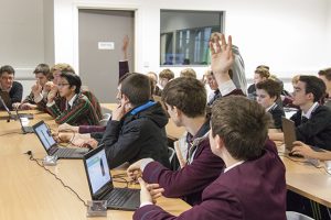 a group of people sitting at a table in front of a laptop computer