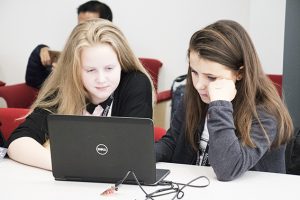 a group of people sitting at a table using a laptop computer