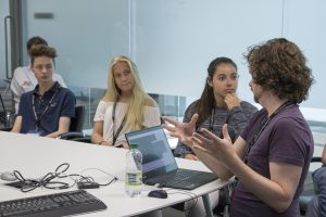 a group of people sitting at a table using a laptop computer