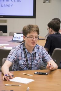 a group of people sitting at a table using a laptop