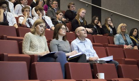 Andreas Varady et al. sitting in front of a crowd