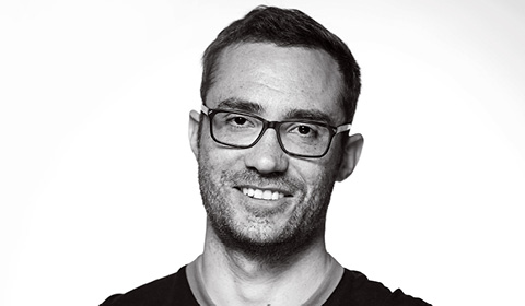 a man wearing glasses and smiling at the camera