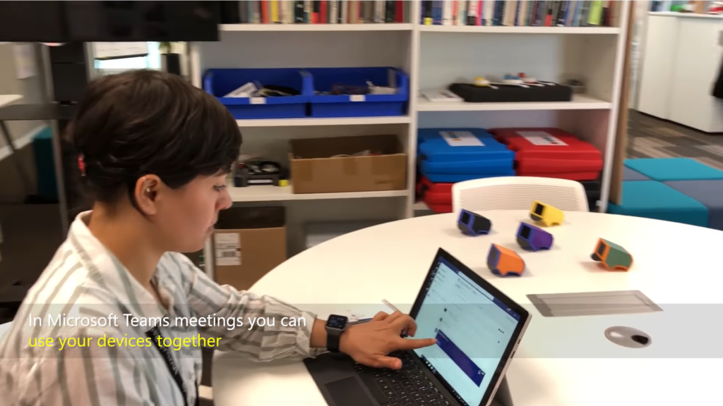 A woman is sat at a table looking at her laptop