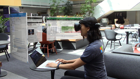 A user sits in a café with three large, private, virtual displays.