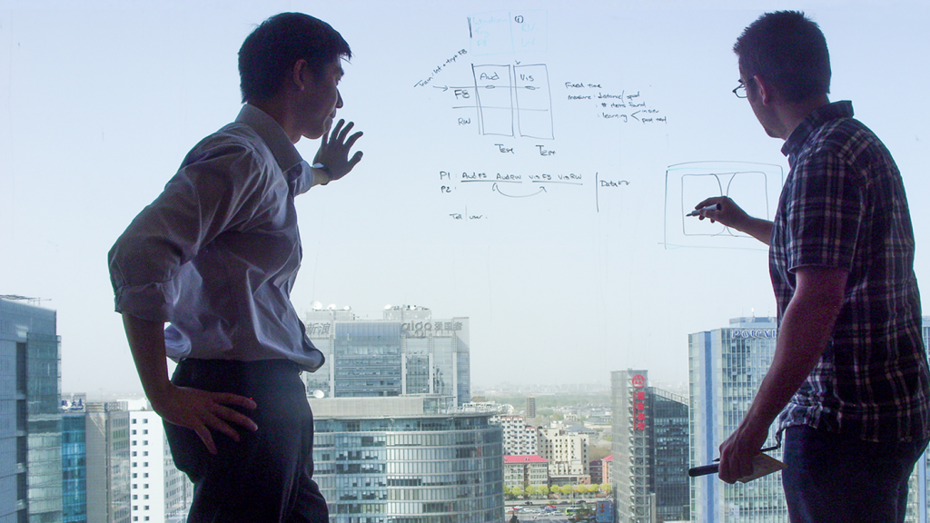 Two guys writing equations on a window in Asia