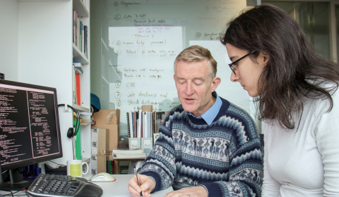 Simon Peyton Jones writing with a fellow researcher at a desk