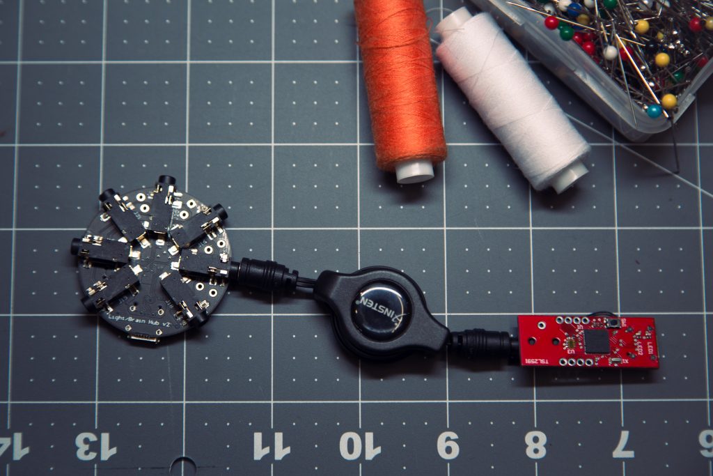 For the fashion application, the plug-and-play microcontroller technology included two core hardware components, both custom-made with SAMD21 microcontrollers: the “brain” and the “beads.” Each of the color-coded beads, or sensors, responded to a different stimulus. The red bead (above, right) is a light sensor bead.