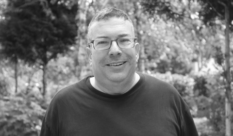 a man wearing glasses and smiling at the camera