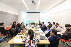 a group of people sitting at a table using a laptop computer