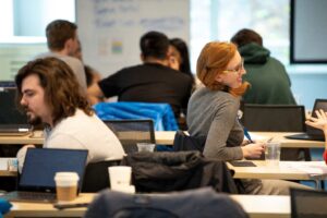 a group of people sitting at a desk looking at a laptop