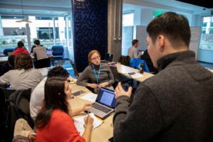a group of people sitting in front of a laptop