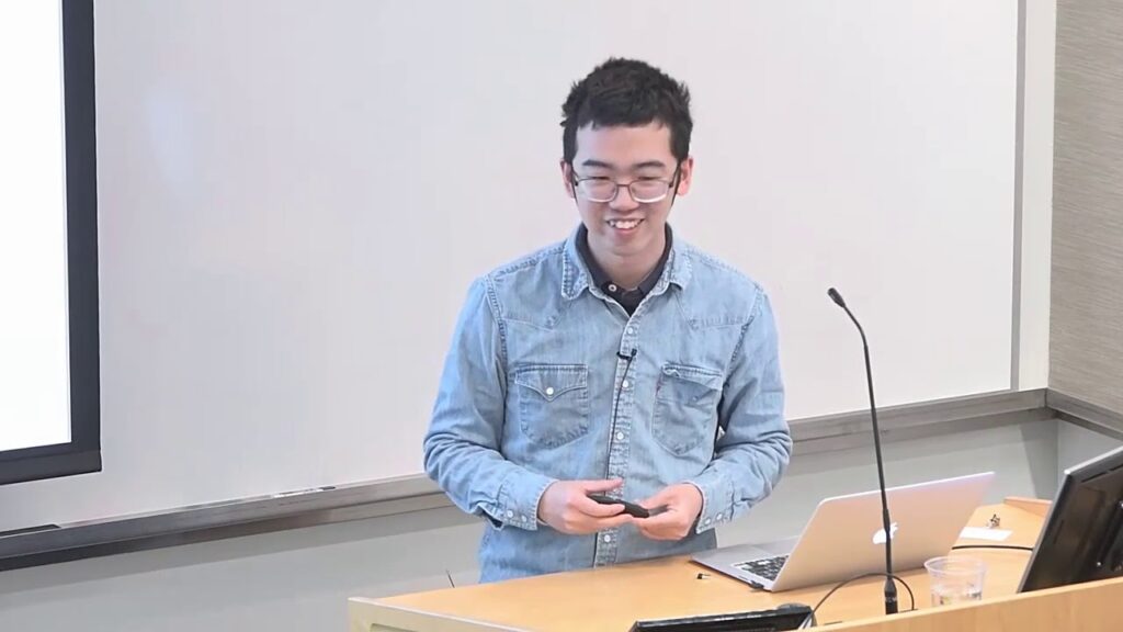 a person sitting at a table with a laptop and smiling at the camera