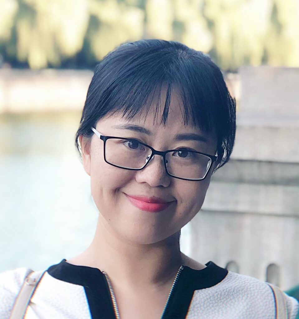 a woman wearing glasses and smiling at the camera