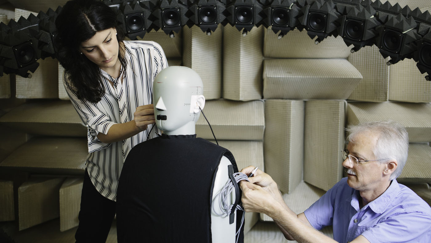 audio and acoustics: woman and man setting up a dummy in anachoic chamber