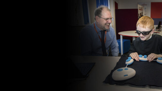 Young blind person learning to code tactilely using Code Jumper pods as teacher looks on. Photo by Jonathan Banks.