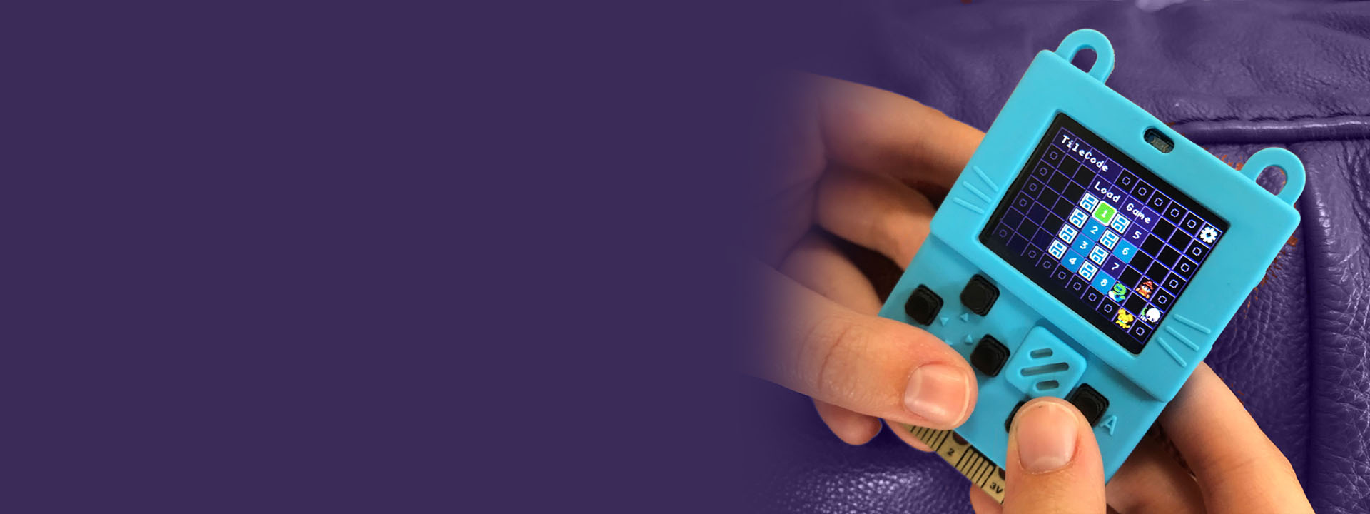 TileCode header: hands holding a small game device