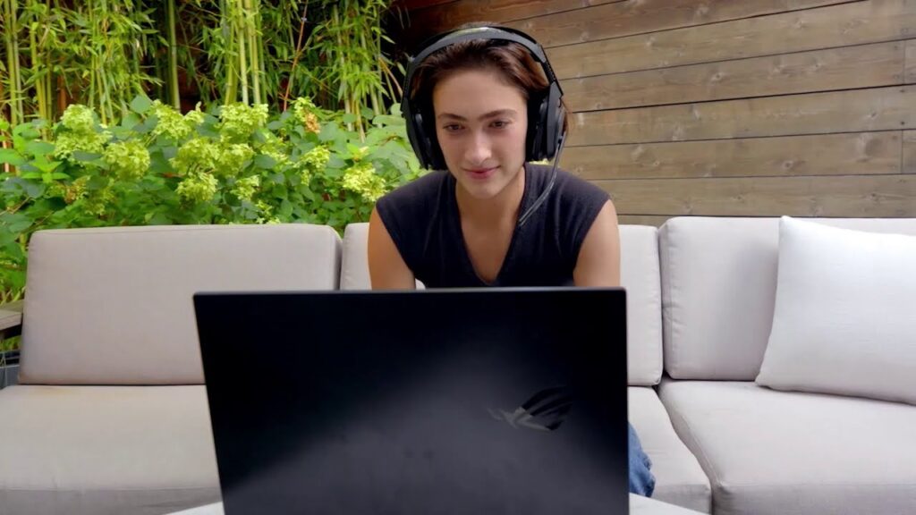 Ester Baiget sitting at a table with a laptop and smiling at the camera
