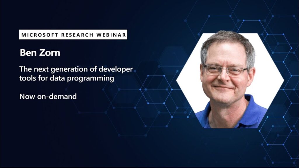 a man with a laptop and smiling at the camera