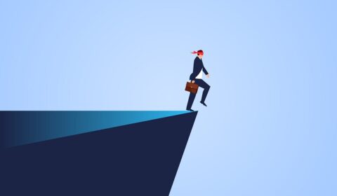 blindfolded businessman at edge of a cliff