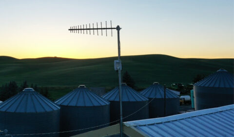 FarmVibes - photo of silos and an antenna against a sunset sky