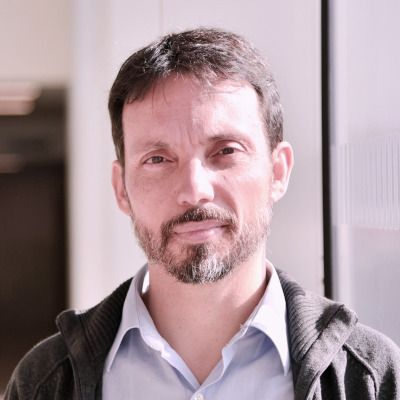 a man wearing a suit and tie smiling and looking at the camera