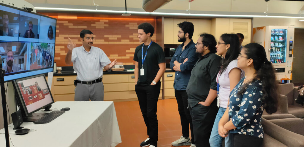 Trevor Noah and others standing in a room receiving instruction on how to use HyWay