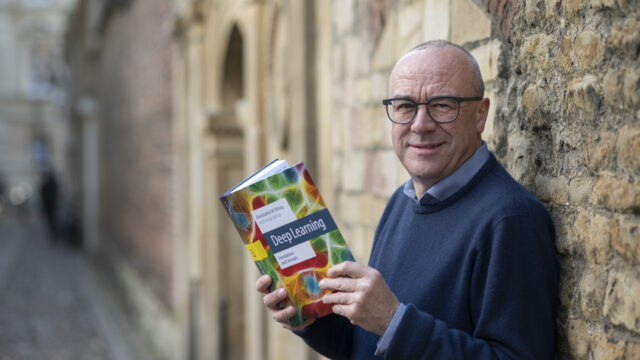 Chris Bishop holding a copy of his book Deep Learning Foundations and Concepts