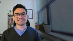 a man wearing glasses and smiling at the camera