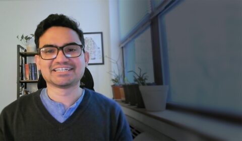 a man wearing glasses and smiling at the camera