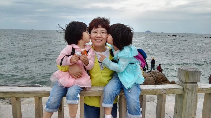 a little girl sitting on a bench in front of a body of water