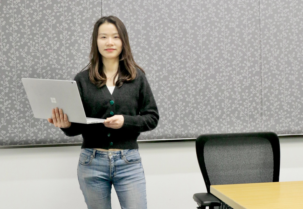 a woman standing in front of a laptop