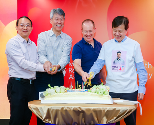 MSR Asia | Peter Lee et al. standing in front of a birthday cake (MSRA 25 years)