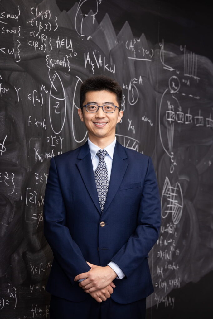 a man in a suit standing in front of a chalkboard