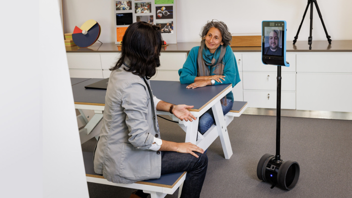 Collab AI group header | two people conversing with another person displayed on a virtual mobile device