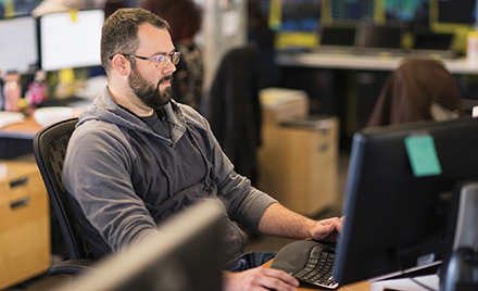 A tech worker stares at a computer monitor.
