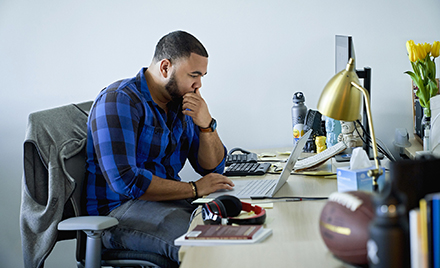 Image of a tech worker at his desk looking at a computer.