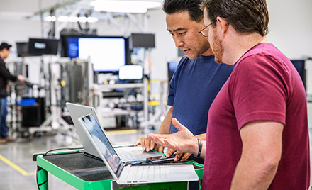 Image of two workers in an office looking at their laptops.
