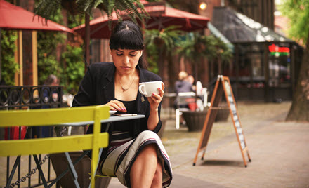 Image of a worker holding a cup of coffee and checking her phone.