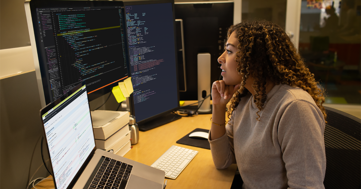 Real people, real offices. Female developer coding at her desk.