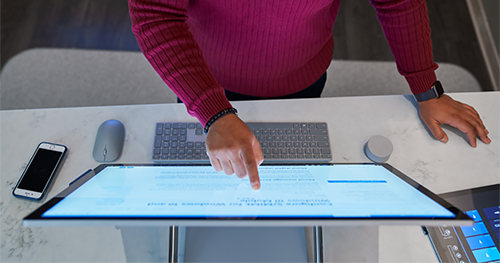 Top down view of a man wearing a dark red shirt working on a Microsoft Surface Studio.