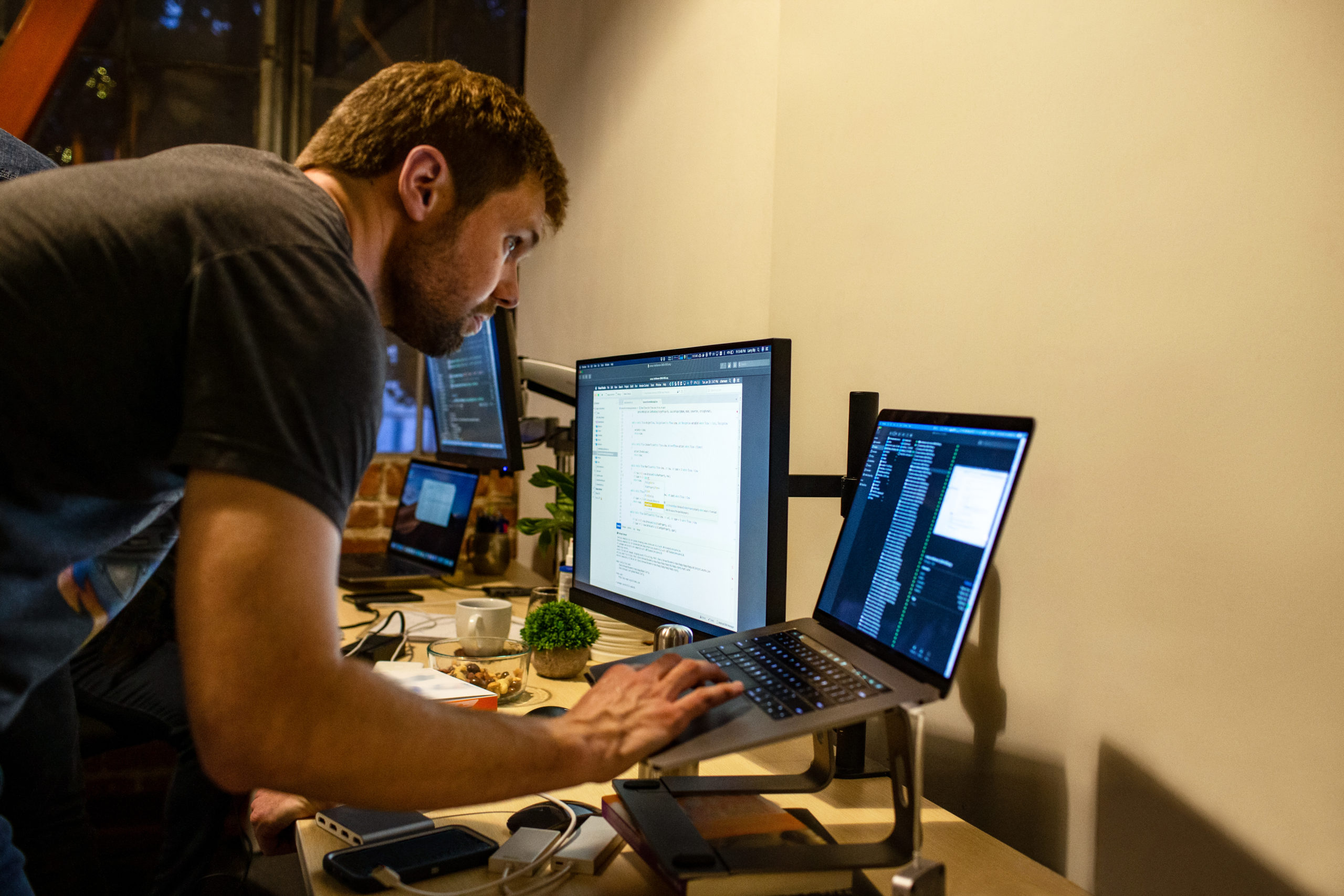 Real people, real offices. Male developer coding while standing at his desk. Code, develop, engineer, Visual Studio, Azure.