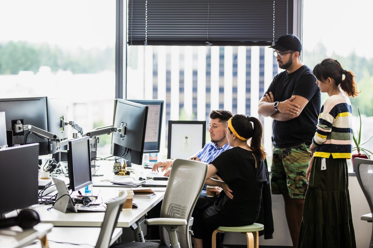 A group of designers collaborate on a project together using shared screen in U.S. office.