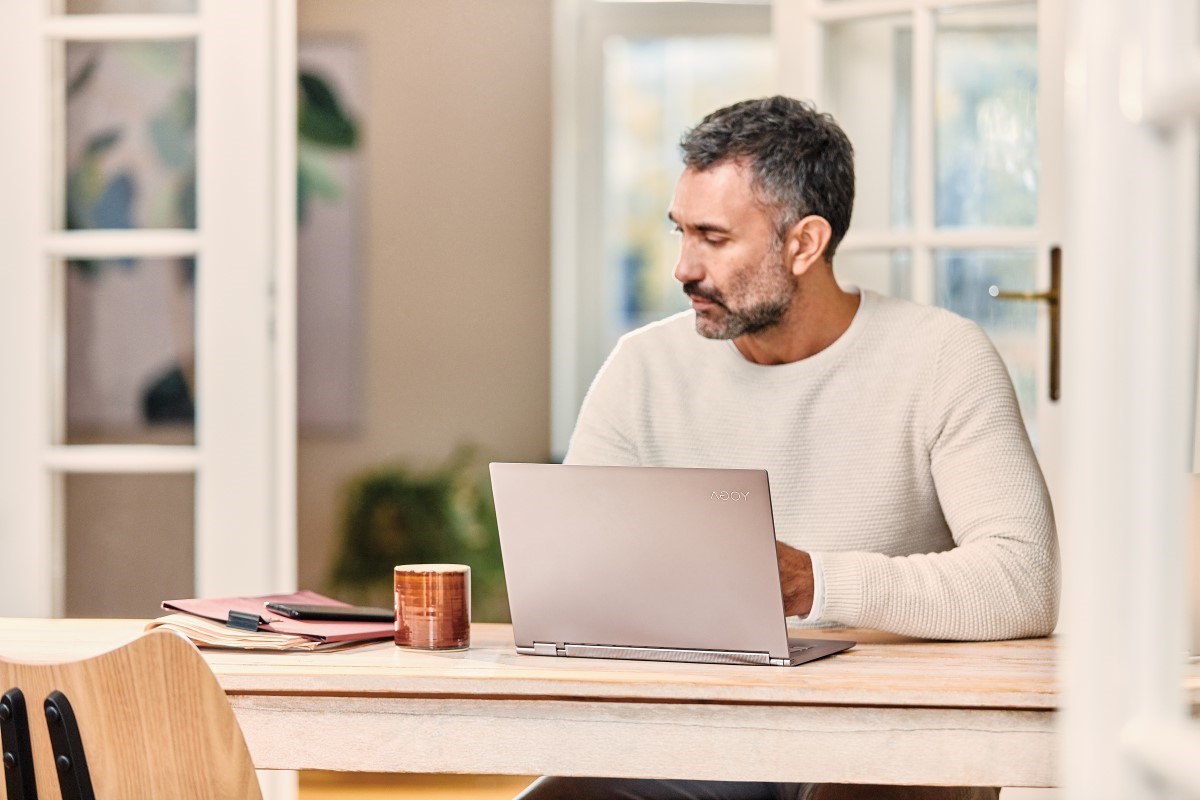 Mobile professional looking at his phone working from home on Lenovo Yoga C930 laptop.