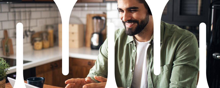 Adult male working from home at kitchen table with headphones on and talking with his hands.