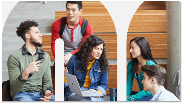 Group of young adults wearing backpacks sit on bleachers surrounding laptop.