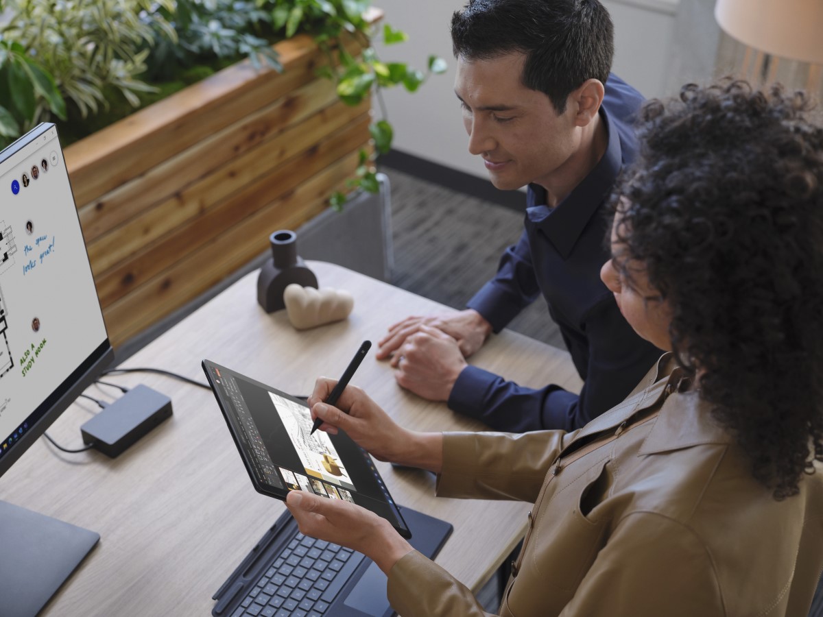 Two adults collaborating while standing at a desk.