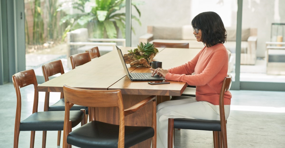 Woman working at dining room table on laptop.